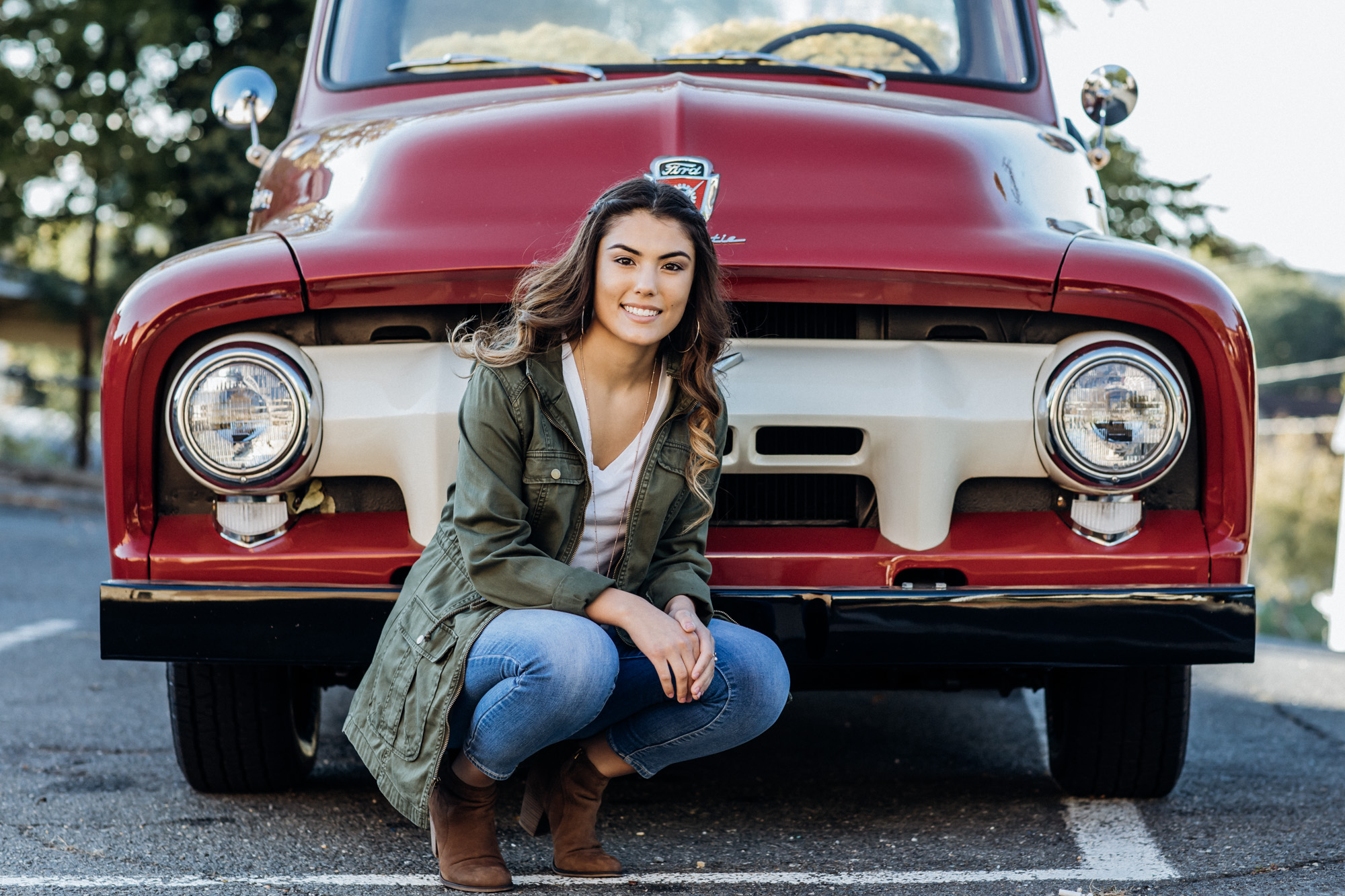 girl kneeling in front of old truck for senior portraits in warrantor Virginia